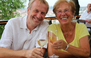 A photo of a man and woman toasting classes of white wine.
