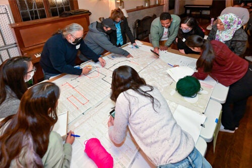 A group of people work on and study a large map laid out on a table.