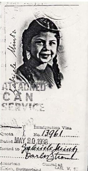 A weathered 1938 immigration visa document with hand-written and stamped text,with a blackand white photo of a young smiling girl with braided hair.