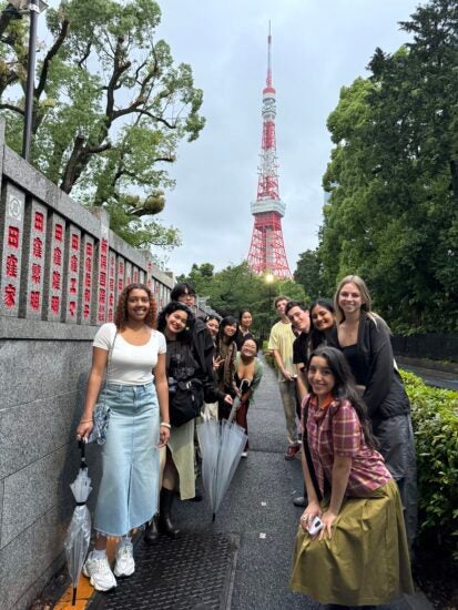 People pose on a Japanese street with Tokyo Tower in the background.