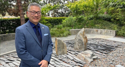 Jon Kaji stands in front of a rock sculpture in USC’s Nisei Garden