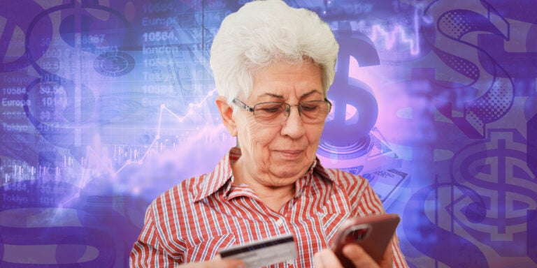 An elderly woman holds a credit card and looks at a smartphone against a graphic background suggestive of finances