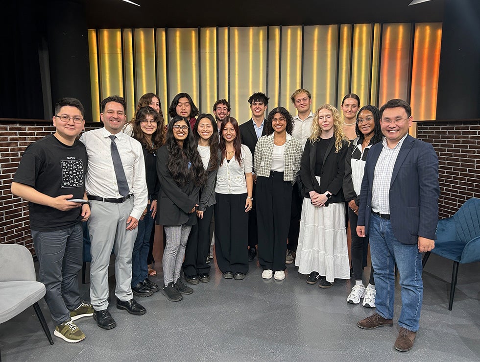 Group of students, their instructor and a broadcaster smile