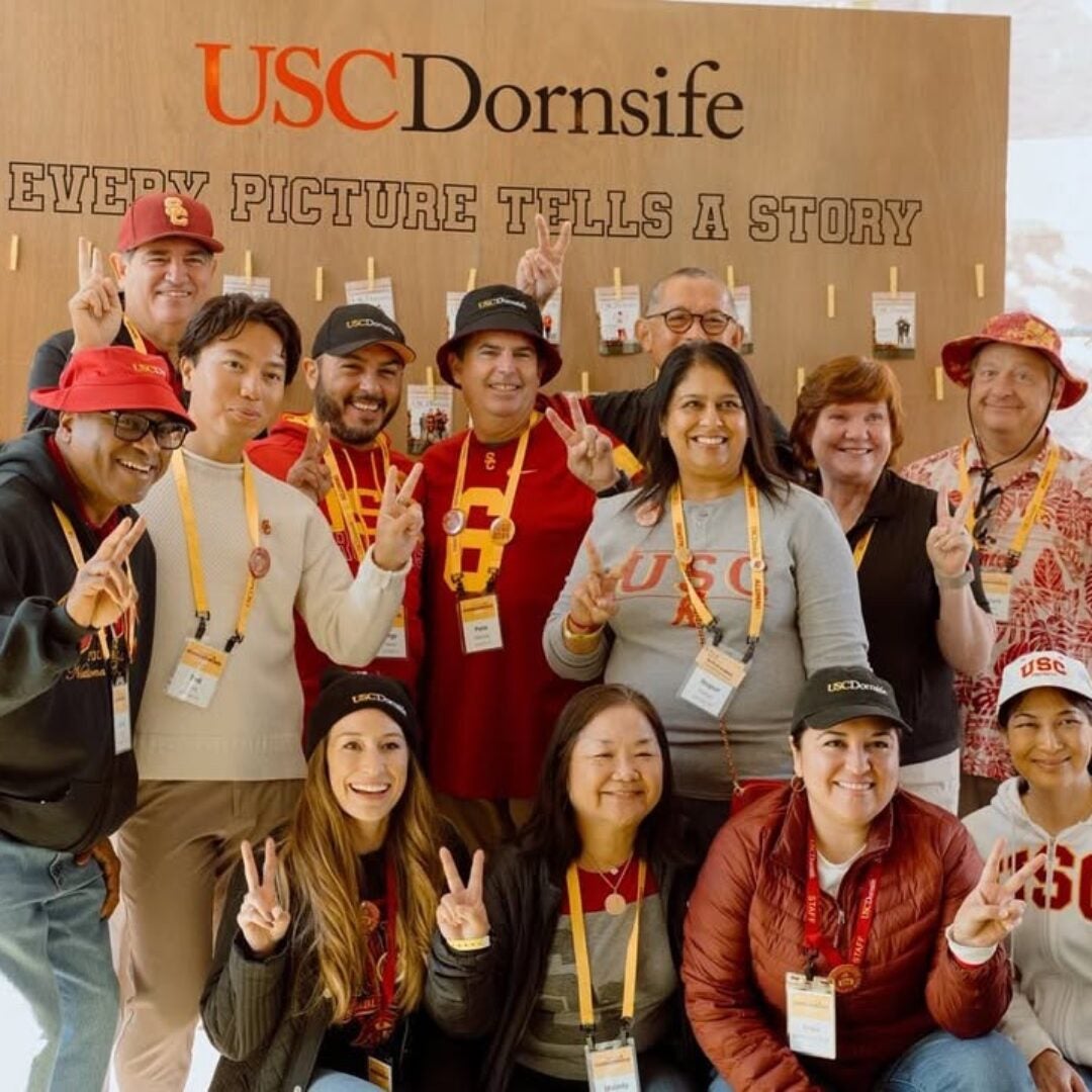 People make the fight on sign in front of a back drop that says USC Dornsife Every Picture Tells A Story