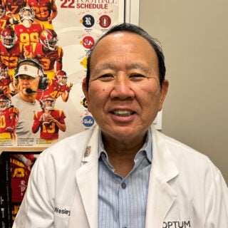 Wesley Mizutani stands in front of a USC Trojan Football poster