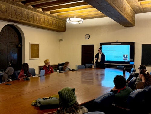 Evan Williams gives a slide presentation to students gathered around a conference room table