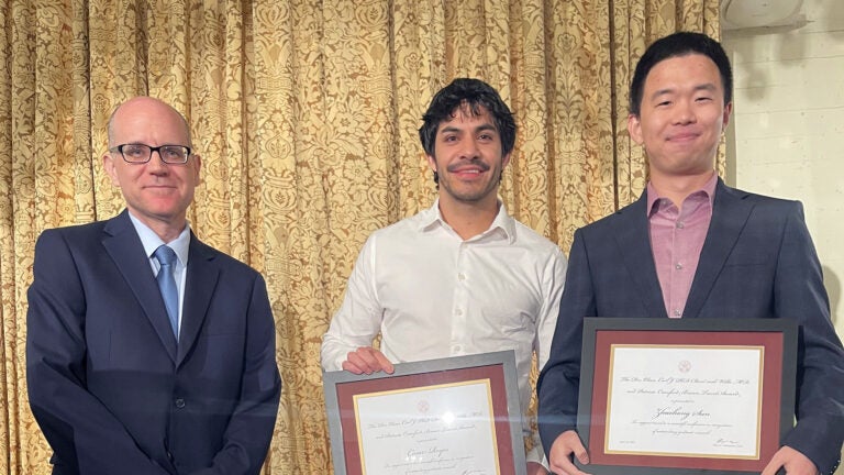 Students Cesar Reyes and Zhaohong Sun stand with chemistry department chair Barry Thompson and display awards