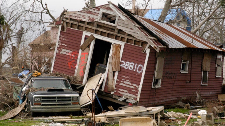 Photo of house collapsing on its side.