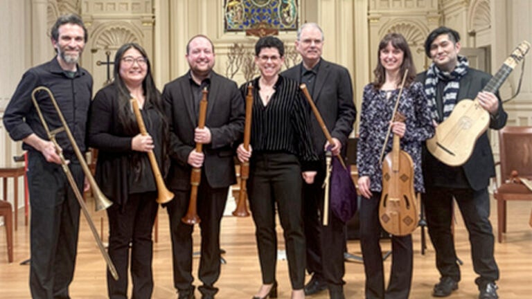 Seven musicians pose together with their instruments