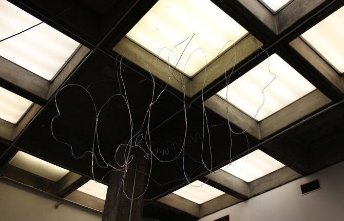 Silver wire sculpture photographed with overhead ceiling lights.