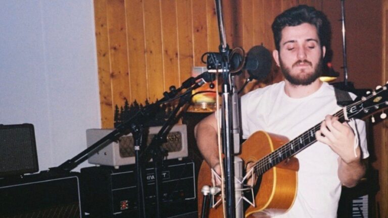 Mackin Carroll plays guitar in a recording studio.