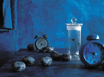 Painting of two alarm clocks, stones, and a vase(?) containing a goldfish(?), all cast in a blue light.