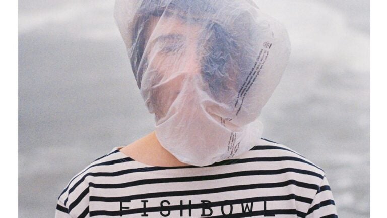 Album cover. A person in a striped shirt wears a bag over their head. Text reads 