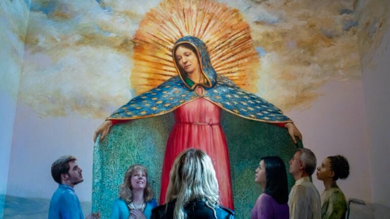 A blonde woman looks at an illustration of the Virgin Mary.