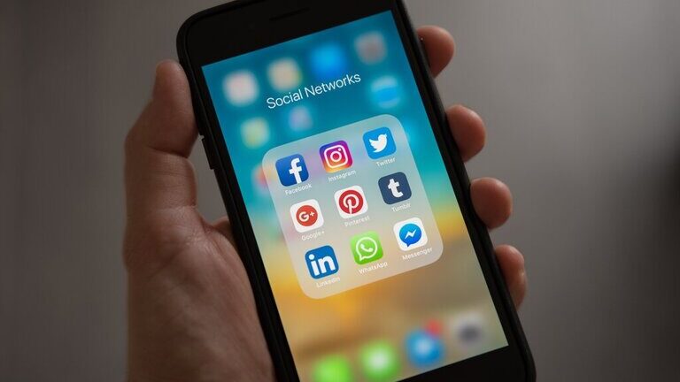 A photo of the screen of an Apple Iphone, showing social medias apps such as Facebook, Instagram, Twitter, and LinkedIn.