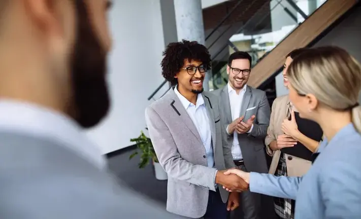 A guy is shaking hands with a woman in a group setting