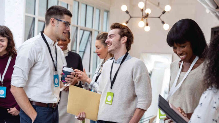 there are 5 people in the photo, 2 men are talking to each other, 2 women are discussing, they're all at an entrepreneur networking event