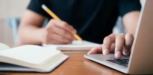 Cropped man writing and using his laptop