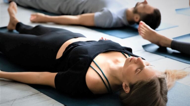 A photo of people doing Yoga Therapy laying down on a Yoga Mat