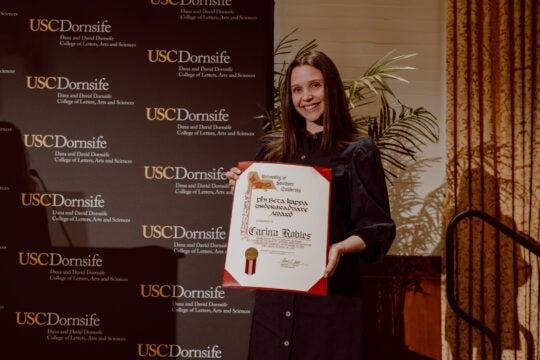 Undergraduate Award recipient Carina Robles smiling while holding award certificate