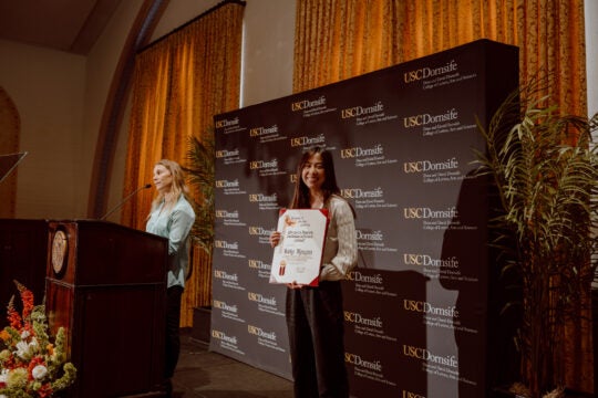 Undergraduate Award recipient Kelly Nguyen smiling while holding award certificate