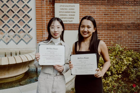 Two Inductees smiling while holding membership certificates.