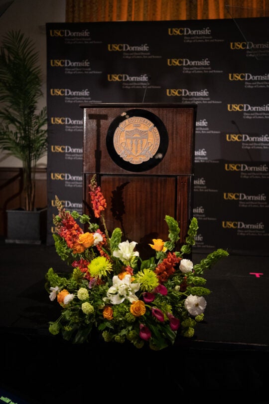 Podium with USC Seal. Florals on floor in front of podium.
