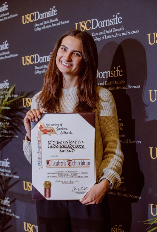 Award Recipient Elizabeth Tchitchkan standing and smiling while holding award certificate.
