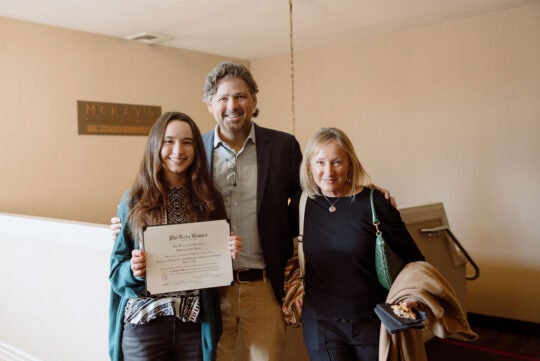 Inductee holding certificate, standing with guests.