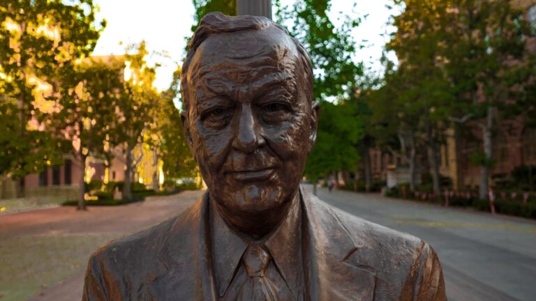 A picture of a bronze statue of an older gentleman on Trousdale Pkwy.