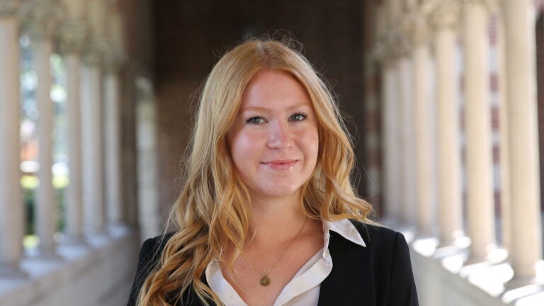a female with blonde hair, wearing a white blouse and a black blazer.