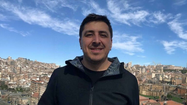 Photo of Pablo with a blue sky background and ai generated buildings