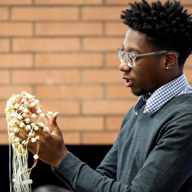 Male student holding brain scan device