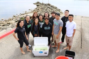 Students at Port of Los Angeles High School, posing near the water before releasing juvenile white seabass after raising them in their classroom.
