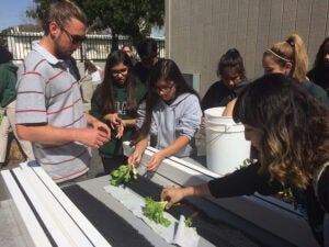 A coordinator of the Aquaponics Program guides students in building and assembling the new aquponic tank at Port of Los Angeles.