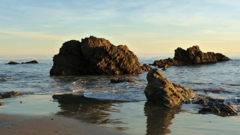 Image of the ocean and rocks at sunset at Lechuza Beach in Malibu, CA.