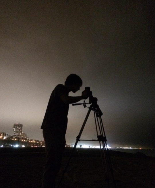 Researchers deploying technology methods on a tripod at night with a dark sky in the background.