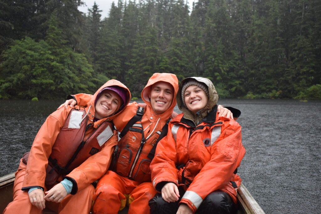 Claudia, Tanner, and Kesten sitting on a boat in the water, learning about the latest conservation efforts.