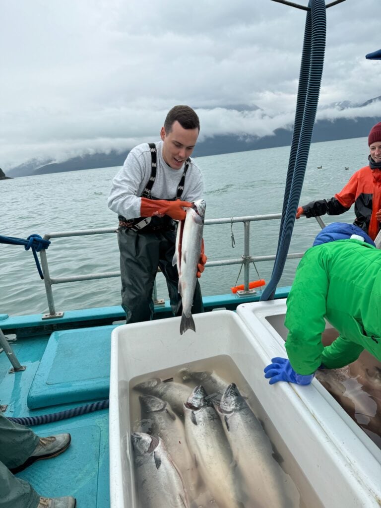 Tanner holding a salmon fish on a boat in Alaska.