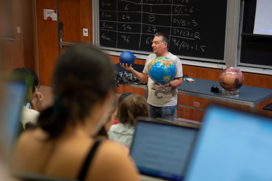 Professor Vahe Peroomian holds a globe while lecturing in Stabler Hall.