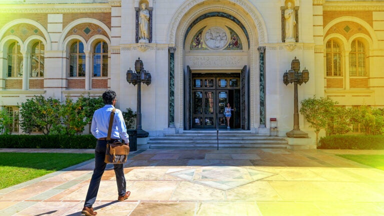 Man with leather bag walking towards library entrance
