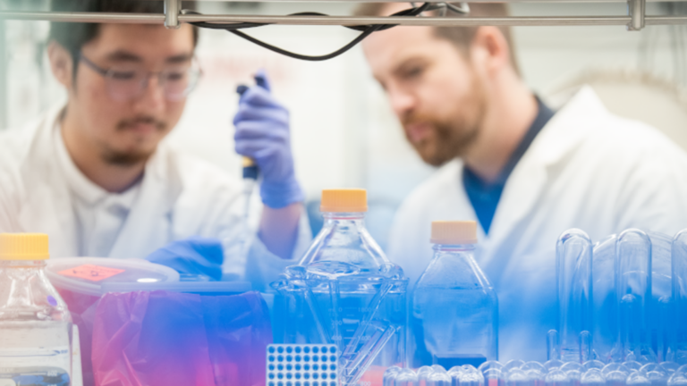 Two men in a lab working with a pipette