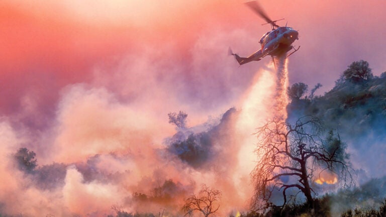 Red sky with fire helicopter dousing forest fires
