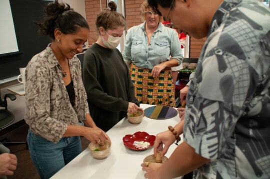 Students use traditional mortar and pestles to grind herbs