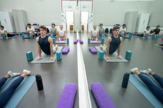 Students participate in a yoga class in a studio gym