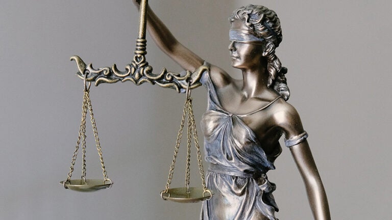 statue of justice with scales on grey background