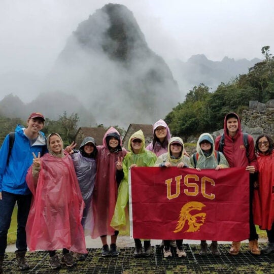 group of students standing with USC flag and Machu Picchu in background