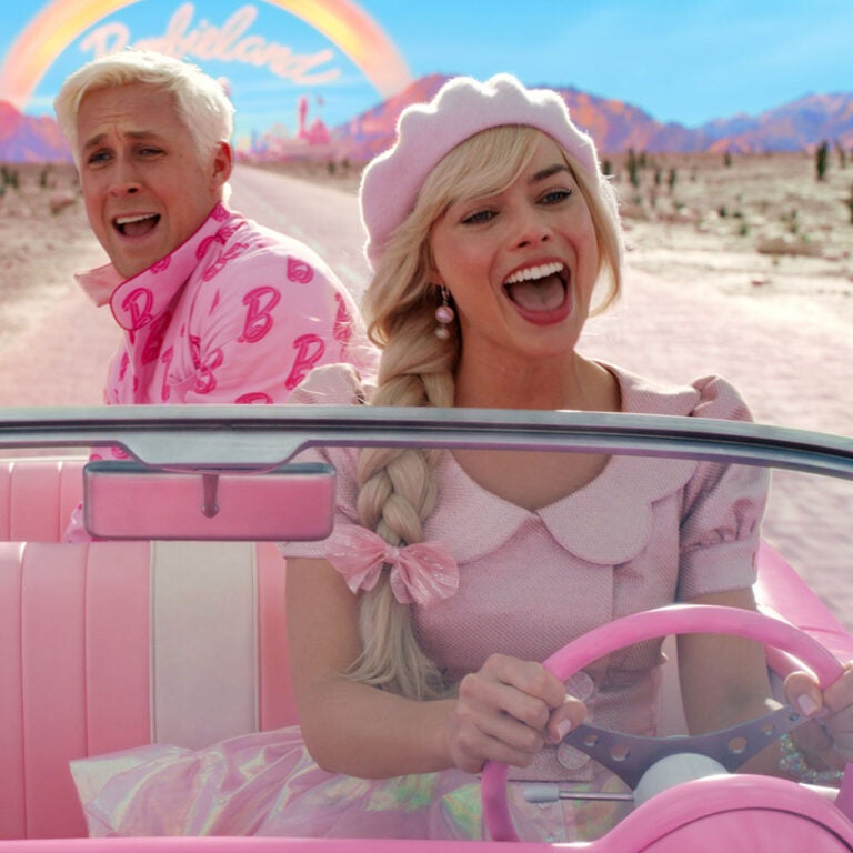 Margot Robbie and Ryan Gosling as Barbie and Ken riding in a pink car in the new Barbie movie.