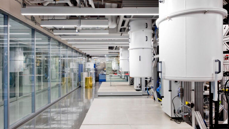 A view inside a quantum computing facility featuring big white machines and a wall of glass