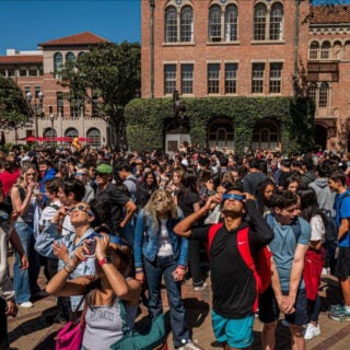 Students wearing special glasses gather on campus to view the eclipse.